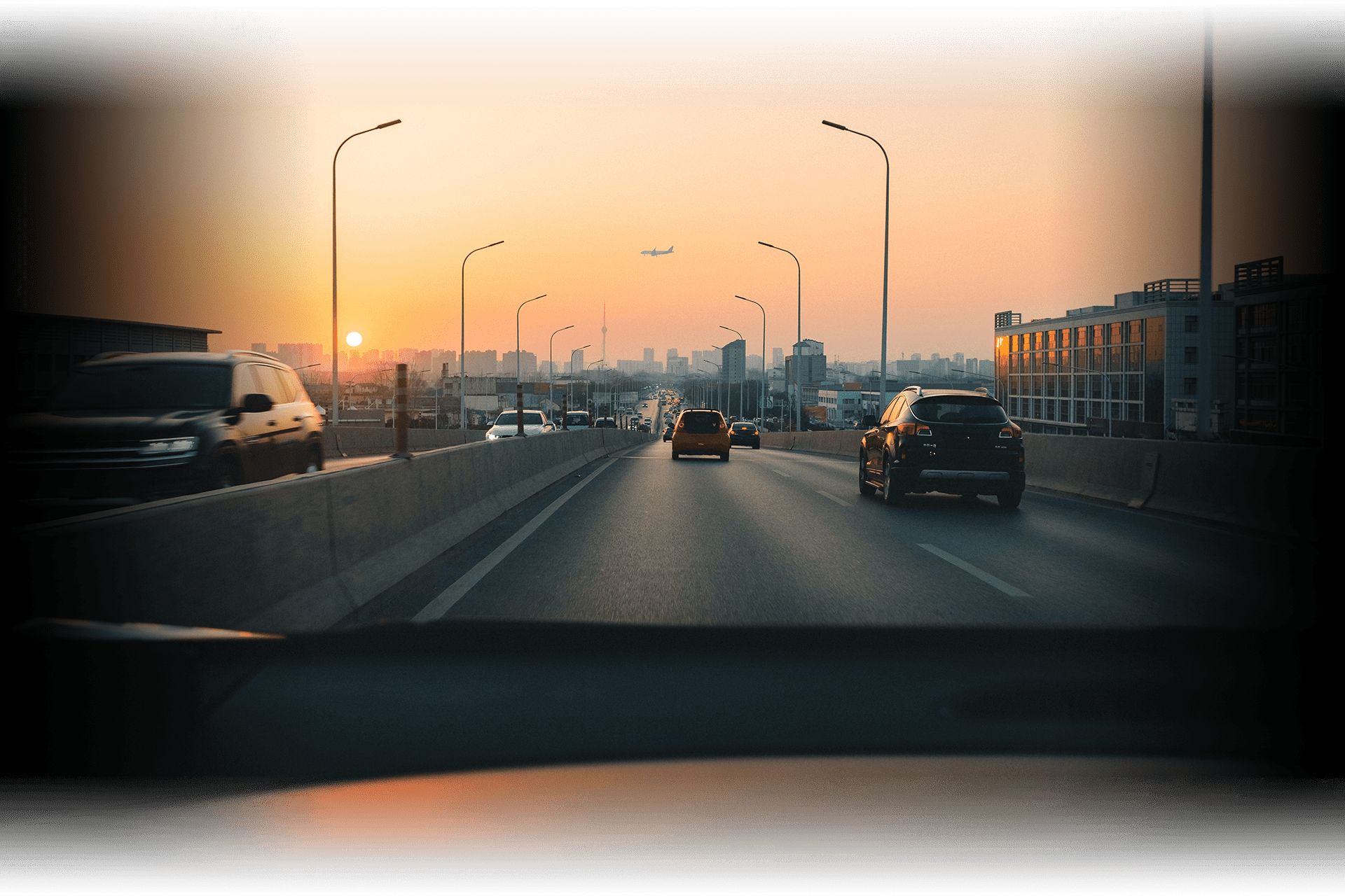 a view out the windshield of a vehicle heading into the destination city during a sunset on a highway with an abstract destination marker at a distant