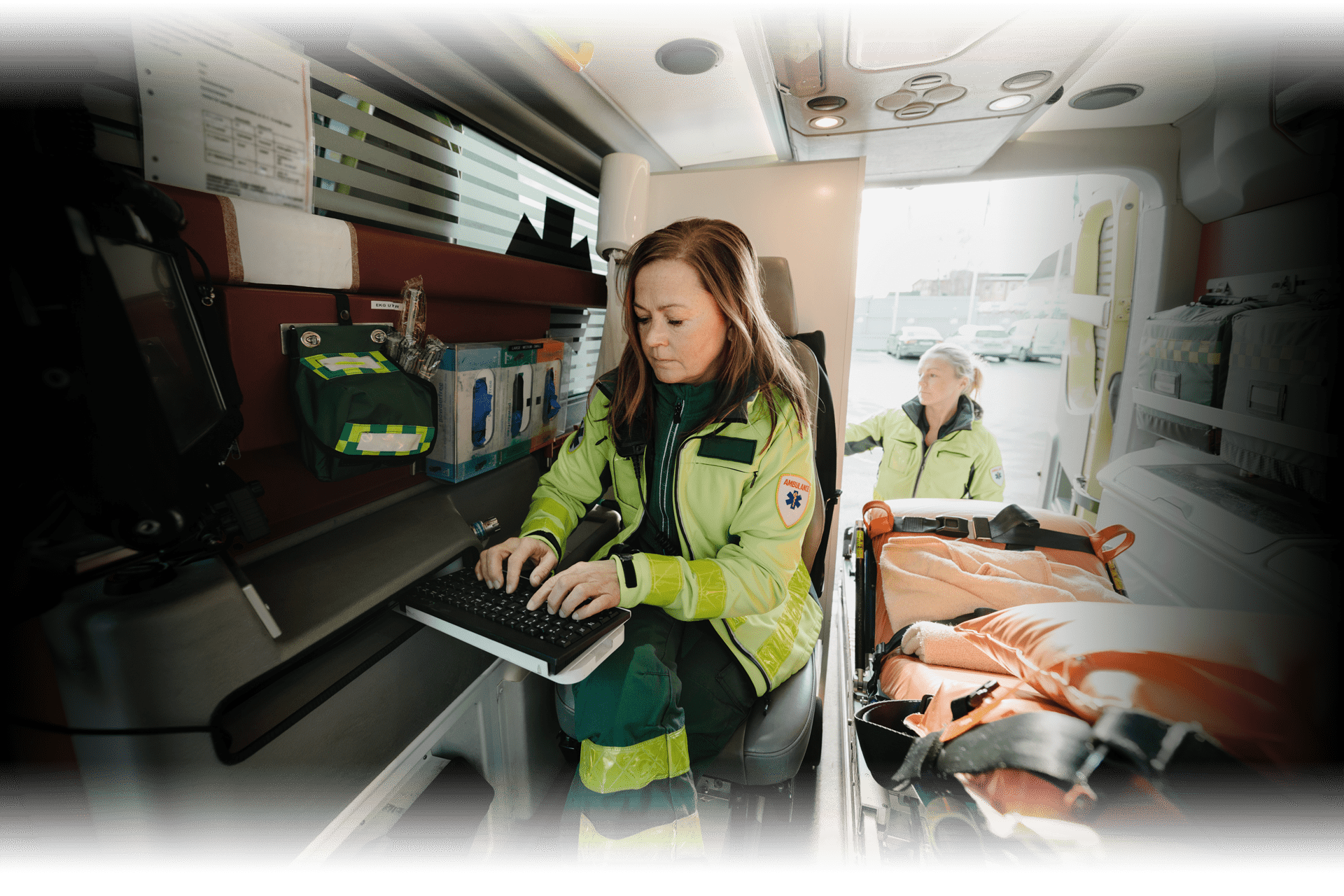 emergency responders getting ready to headout out in the back of an ambulence with electric blue highlight of a computer screen indicating the receipt of incident data